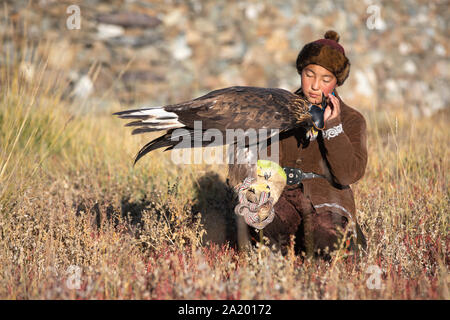 Kazakh traditionnel eagle chasseresse de flatter son golden eagle qui est utilisé pour chasser pour fox et fourrure de lapin. Ulgii, l'ouest de la Mongolie. Banque D'Images