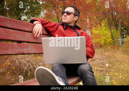 Freelancer in autumn Park. La révision de l'éditeur de magazines nouvel article reçu par courriel. homme surf web sur un ordinateur portable connecté à un réseau wifi. La préparation d'étudiants fo Banque D'Images