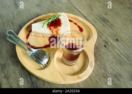 Le gâteau au fromage Camembert garnie de sirop de fraise avec cuillère et fourchette sur une plaque de bois, un aliment sucré avec brown le tableau en arrière-plan Banque D'Images