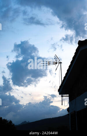 Antenne de télévision d'une maison avec ciel nuageux dans l'arrière-plan au coucher du soleil Banque D'Images