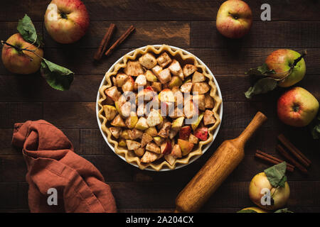Cuisson de la tarte aux pommes faite maison avec une croûte feuilletée et la cannelle. Vue de dessus sur une table en bois rustique, d'arrière-plan. Moody sombre automne still life Banque D'Images