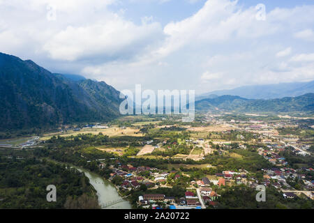 Vue de dessus, superbe vue aérienne du beau village de Vang Vieng avec la rivière Nam Song qui coule à travers. Banque D'Images