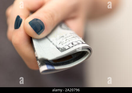 Hand holding folded paiement billets de cent nouveaux dollars us le paiement de factures, procédure de paiement ou pot-de-vin, salaire, Close up Banque D'Images