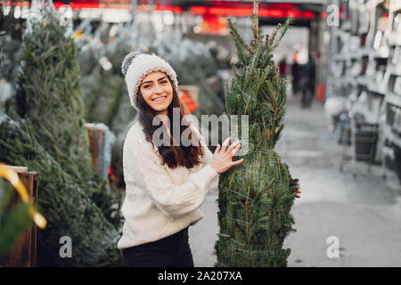 Brunette mignon dans un chandail blanc avec arbre de Noël Banque D'Images