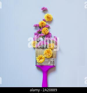 Fleurs d'automne jaune et rose et un pinceau sur fond bleu. Art minimal de mode automne concept. Banque D'Images