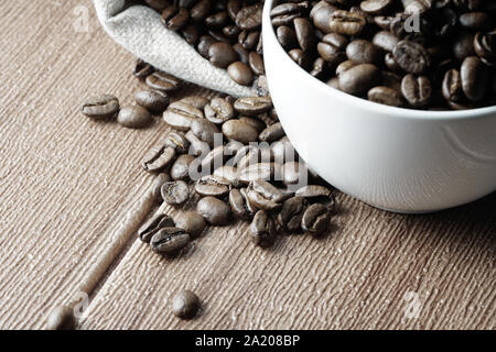 Grains de café dans une tasse blanche sur une surface en bois Banque D'Images