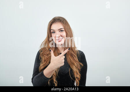 Fille aux cheveux brun en robe noire sur fond blanc isolé montre les émotions Banque D'Images