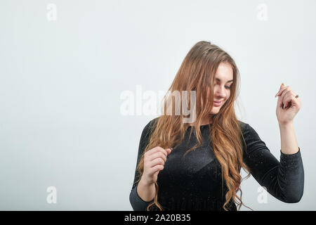 Fille aux cheveux brun en robe noire sur fond blanc isolé montre les émotions Banque D'Images