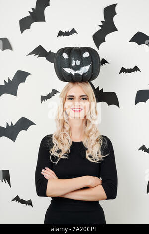 Happy young woman standing with pumpkin peint en noir sur la tête. Banque D'Images