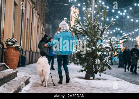 Femme marche vers le bas avec chien blanc par alley. Banque D'Images