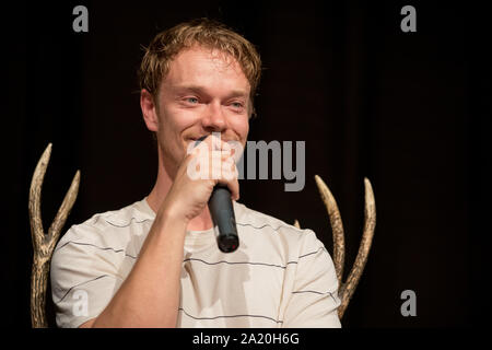 27 septembre 2019, Basse-Saxe, Langenhagen : l'acteur britannique Alfie Allen parle de la 'Game of Thrones' tir à l 'événement ventilateur trône con' dans un hôtel à l'aéroport Hannover-Langenhagen. Selon les organisateurs, environ 800 fans sont venus pour être près de leurs idoles de la série. Photo : Moritz Frankenberg/dpa Banque D'Images