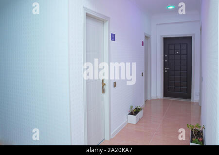 La lumière rose de l'espace .porte Eclairage intérieur design . Murs blancs et porte dans couloir avec plancher en bois . Photo de carré long home couloir avec Banque D'Images