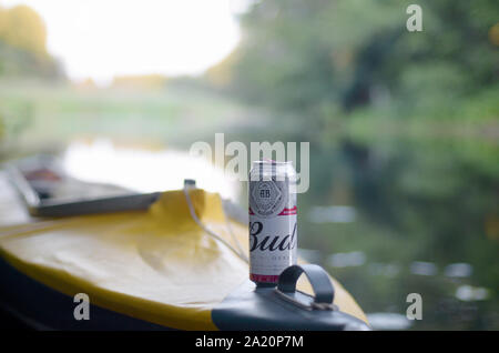 Kiev, UKRAINE - le 10 août 2019 : la bière Budweiser Bud peut sur jaune kayak à l'extérieur dans la rivière et arbres vert arrière-plan flou. Budweiser est l'un des Banque D'Images