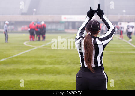 Vue arrière de l'arbitre de football américain féminin signaux donnant aux joueurs professionnels au cours de match sur le terrain du stade Banque D'Images