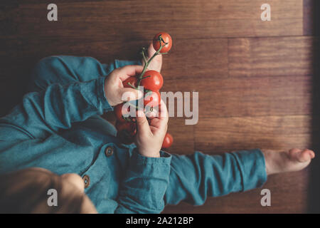 Petit bébé explore les tomates rouges. Banque D'Images