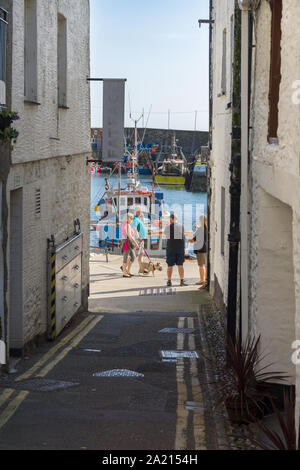 Les touristes à pied par le port de la ville côtière de Mevagissey le village est connu pour ses rues étroites et les ruelles et est un port de pêche de travail Banque D'Images