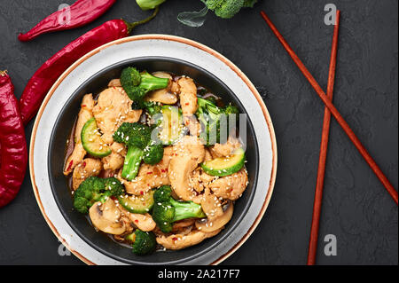 Poulet au Hunan bol noir dark slate à fond. Poulet Hunan est chinois ou l'indo-chinoise plat à emporter avec brocoli, courgettes, shiitake Banque D'Images