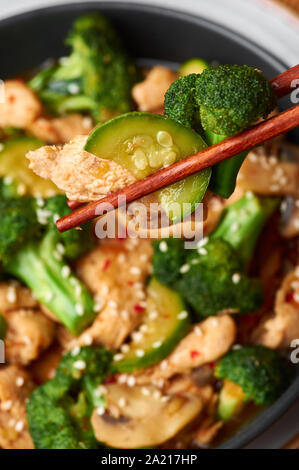 Poulet au Hunan bol noir dark slate à fond. Poulet Hunan est chinois ou l'indo-chinoise plat à emporter avec brocoli, courgettes, shiitake Banque D'Images