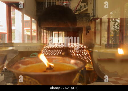 Gros plan d'une flamme de lampe et Série de petites lampes à huile dans un monastère bouddhiste tibétain temple à Sikkim, Inde Banque D'Images