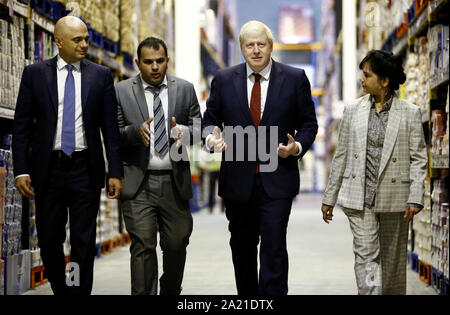 Premier ministre Boris Johnson (centre droit) et le Chancelier de l'Échiquier Sajid Javid (gauche) sont représentées autour par les responsables d'exploitation Kamal Din et Sameena Marland, lors d'une visite à Bestway en gros dans Manchester. Banque D'Images