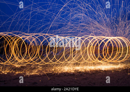 Peinture lumière circulaire à l'aide de la laine d'acier dans la nuit sur la plage. Banque D'Images