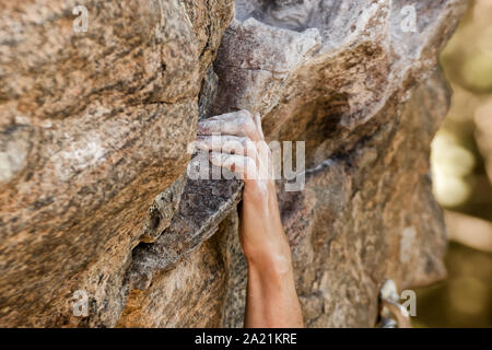 Vue rapprochée du rock Climber's main agrippant tenir sur falaise naturelle. Banque D'Images
