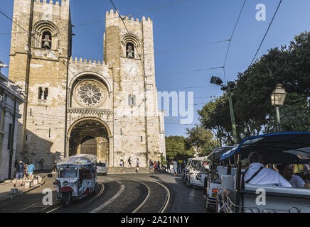 Lisbonne, Portugal - août 2019 : tuktuk touristique en passant par la rue pavée en face de la cathédrale à l'Alfama Banque D'Images