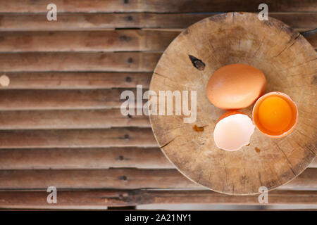 Les oeufs bruns sur une planche à découper en bois il y a un œuf dans la coquille de l'oeuf. Le brown egg a une goutte d'eau parce que c'est la dépose du réfrigérateur Banque D'Images