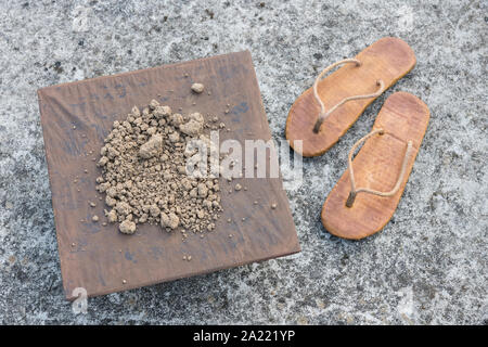 Flipflops hippy usés et carré avec la masse sur la surface du béton. La théorie de la terre plate métaphore, télévision earthers, théories du complot, preuve de la terre plate. Banque D'Images