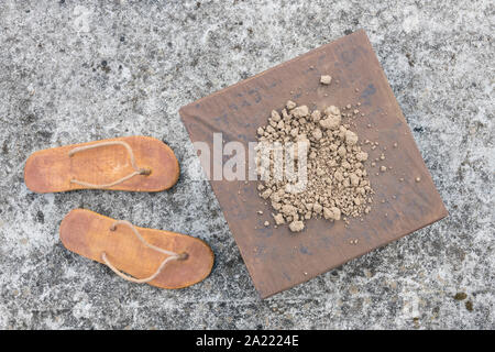 Flipflops hippy usés et carré avec la masse sur la surface du béton. La théorie de la terre plate métaphore, télévision earthers, théories du complot, preuve de la terre plate. Banque D'Images