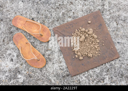 Flipflops hippy usés et carré avec la masse sur la surface du béton. La théorie de la terre plate métaphore, télévision earthers, théories du complot, preuve de la terre plate. Banque D'Images