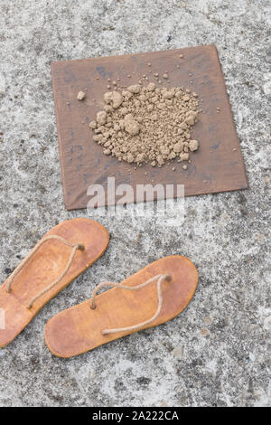 Flipflops hippy usés et carré avec la masse sur la surface du béton. La théorie de la terre plate métaphore, télévision earthers, théories du complot, preuve de la terre plate. Banque D'Images