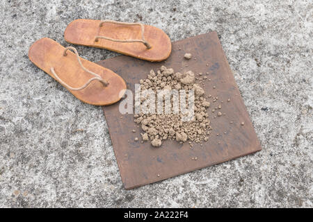 Flipflops hippy usés et carré avec la masse sur la surface du béton. La théorie de la terre plate métaphore, télévision earthers, théories du complot, preuve de la terre plate. Banque D'Images