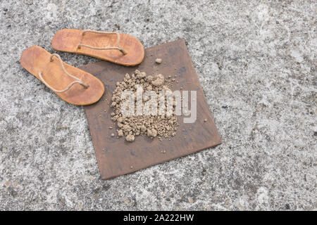 Flipflops hippy usés et carré avec la masse sur la surface du béton. La théorie de la terre plate métaphore, télévision earthers, théories du complot, preuve de la terre plate. Banque D'Images