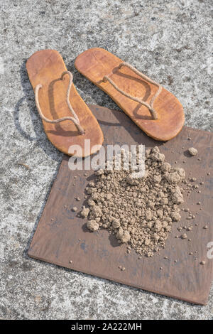 Flipflops hippy usés et carré avec la masse sur la surface du béton. La théorie de la terre plate métaphore, télévision earthers, théories du complot, preuve de la terre plate. Banque D'Images