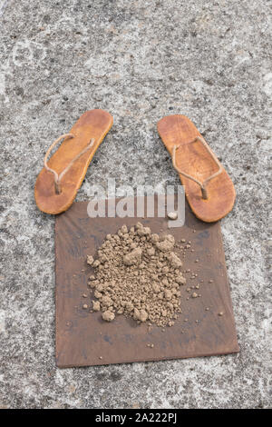 Flipflops hippy usés et carré avec la masse sur la surface du béton. La théorie de la terre plate métaphore, télévision earthers, théories du complot, preuve de la terre plate. Banque D'Images