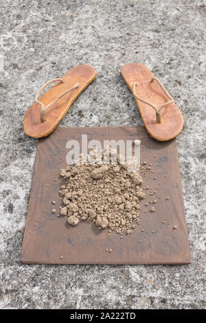 Flipflops hippy usés et carré avec la masse sur la surface du béton. La théorie de la terre plate métaphore, télévision earthers, théories du complot, preuve de la terre plate. Banque D'Images