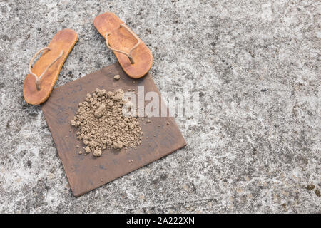 Flipflops hippy usés et carré avec la masse sur la surface du béton. La théorie de la terre plate métaphore, télévision earthers, théories du complot, preuve de la terre plate. Banque D'Images