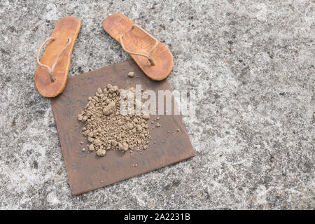 Flipflops hippy usés et carré avec la masse sur la surface du béton. La théorie de la terre plate métaphore, télévision earthers, théories du complot, preuve de la terre plate. Banque D'Images