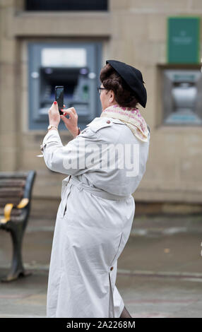 Pays de Galles, Welshpool 1940 week-end de Septembre, 2019. Dame en robe de la période à l'aide de l'appareil photo de téléphone mobile. Banque D'Images