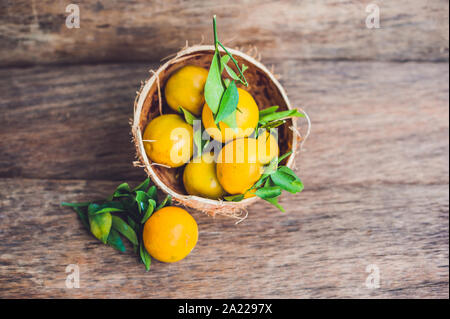 Tangerines fraîches avec des feuilles sur le vieux fond de bois Banque D'Images