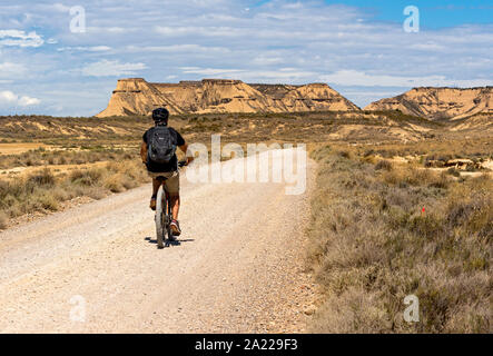 Cycliste sur une route dans le désert de Bardenas Reales, Navarre, Espagne Banque D'Images