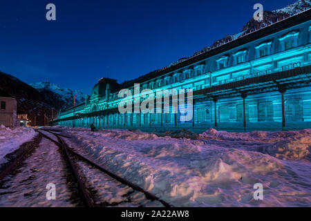 Ancienne gare de Canfranc avec la façade illuminée en bleu sur une nuit d'hiver avec de la neige sur les pistes, Huesca, Aragon, Espagne Banque D'Images