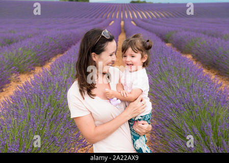 Happy mother and daughter parmi les champs de lavande en été Banque D'Images