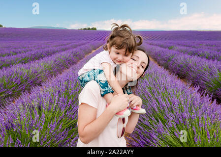 Femme heureuse et petite fille qui marche parmi les champs de lavande en été Banque D'Images