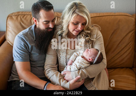 Family holding sleeping newborn fille sur la table à la maison Banque D'Images