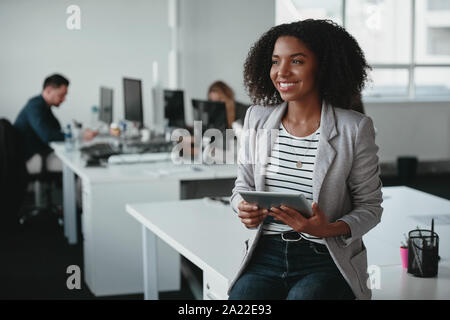 Happy young businesswoman with digital tablet in part en souriant et à la voiture en face de collègue à l'arrière-plan Banque D'Images