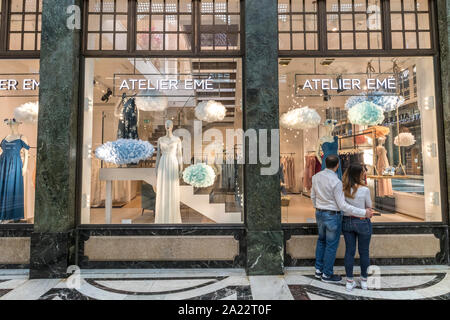 Un couple à la recherche à travers la fenêtre à une boutique de robes de mariée Atelier ,Eme',dans la Galleria San Federico ,une magnifique piscine Art déco shopping arcade à Turin Banque D'Images