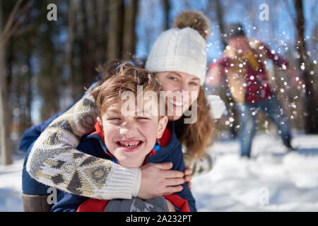 Famille d'une mère, père et enfant garçon s'amusant dans la neige durant la saison d'hiver et lançant des boules de neige au cours d'une lutte ludique Banque D'Images