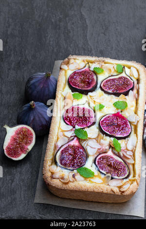 Tarte aux figues maison fromage brie et amandes sur fond noir en noir Banque D'Images